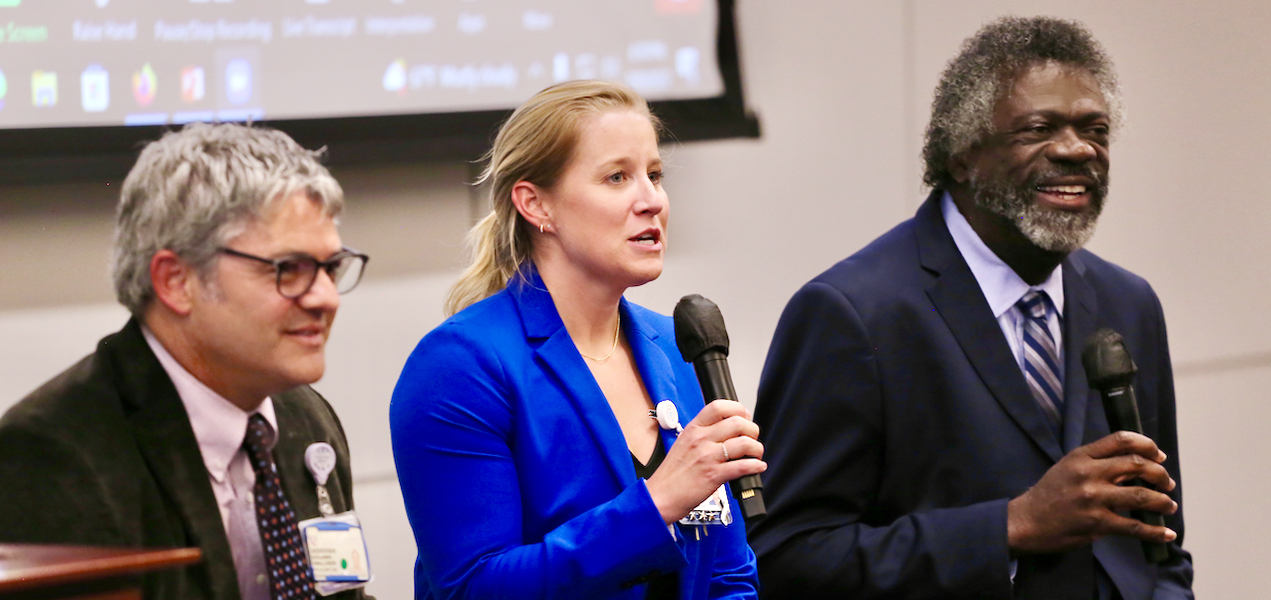 Three Duke University School of Nursing leading faculty members sitting in a row in a lecture-style room holding microphones.