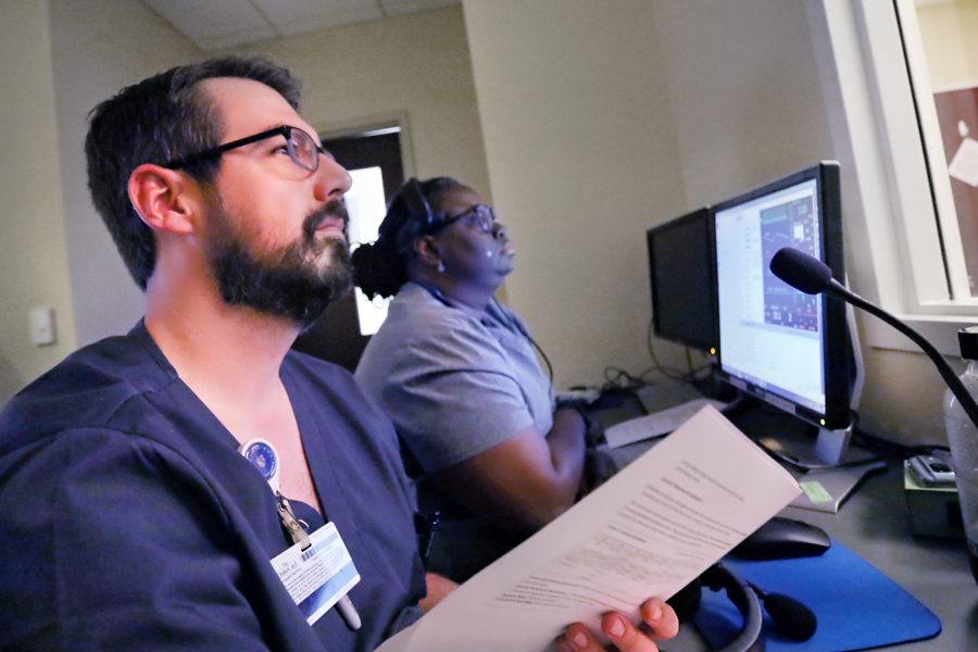 A male Duke University Nursing MSN Health Informatics Student sits infront of health analytics on a monitor beside a female health informatics nursing student. 