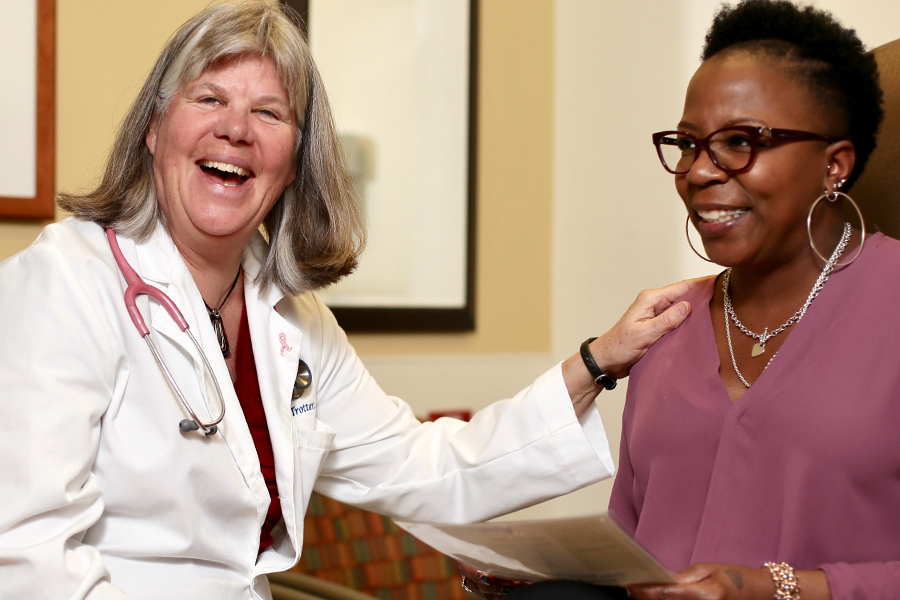 Kathy Trotter, a Duke University School of Nursing faculty member smiles and touches a woman's shoulder. 