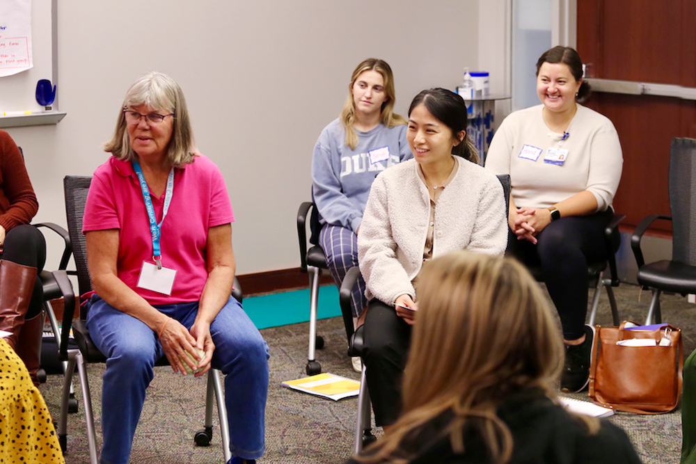 Duke University School of Nursing faculty sit with many students in a group for MSN WH intensives. 