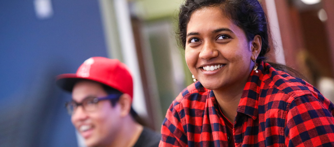 A female Duke University School of Nursing MSN student in a classroom setting smiling broadly. 