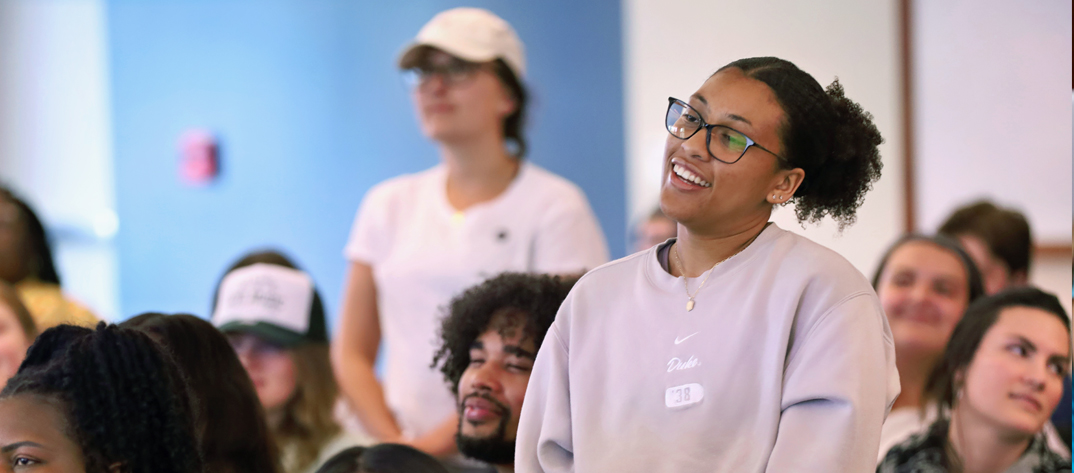 Duke Nursing Student stands in a classroom smiling and asking a question. 