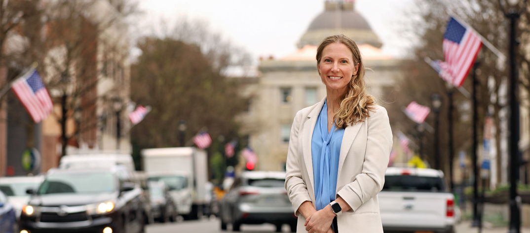 A Duke School of Nursing Faculty Members stands downtown Raleigh in front of the NC State Capital Building