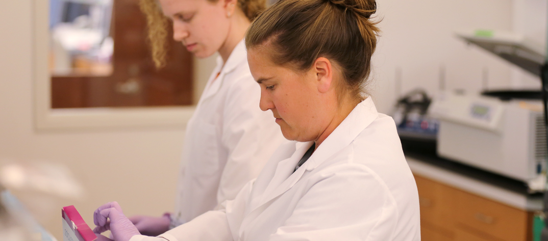 Two PhD students in lab coats doing research