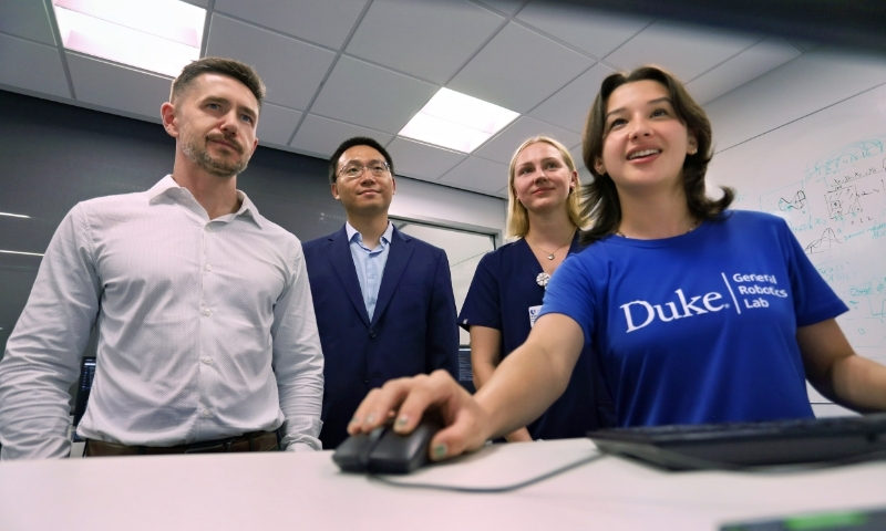 Ryan Shaw with Boyuan Chen, Anna Pienkos, and Nicole Errera working with a robotic arm