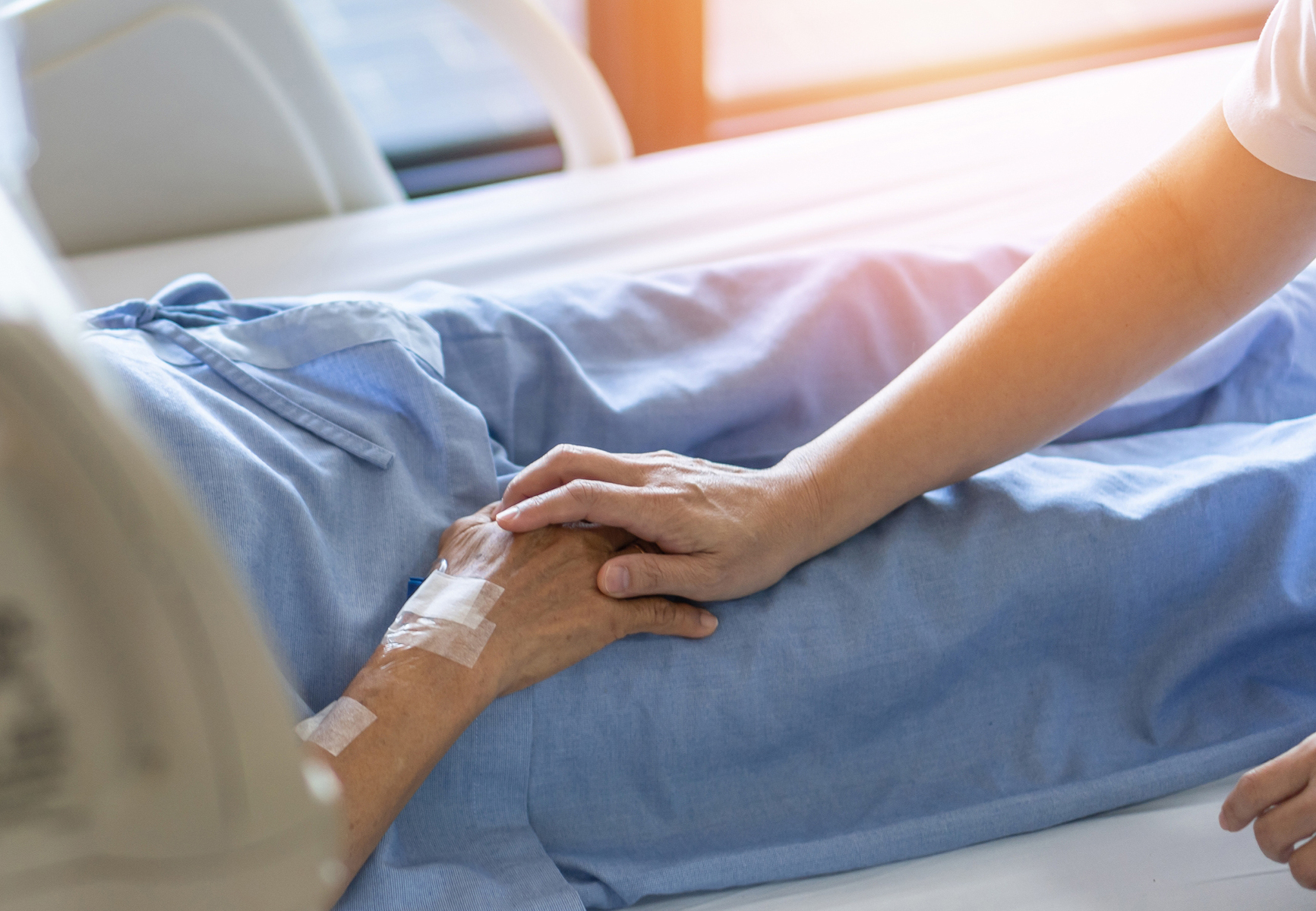 Palliative Care Nurse holding a patient's hand