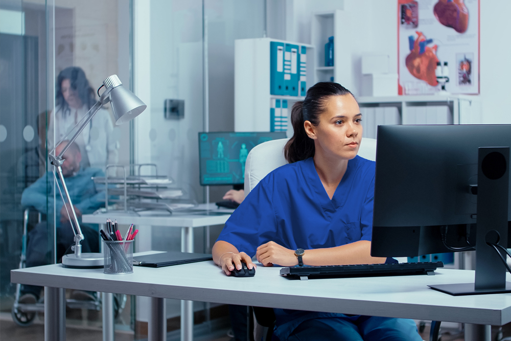 Nurse at desk reviewing computer screen