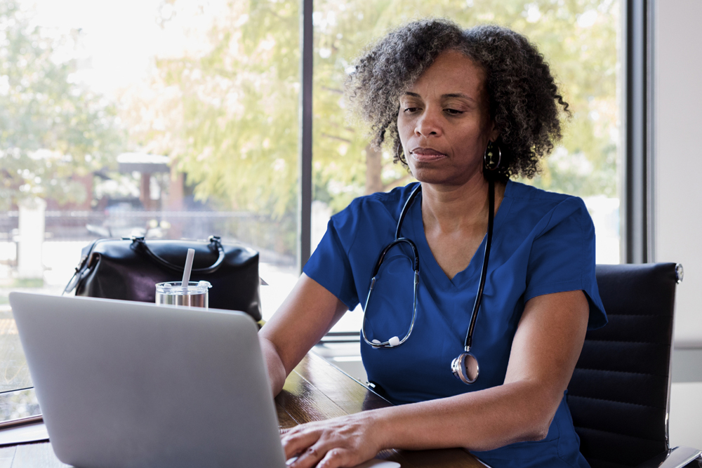 Nurse sitting at desk working on a laptop