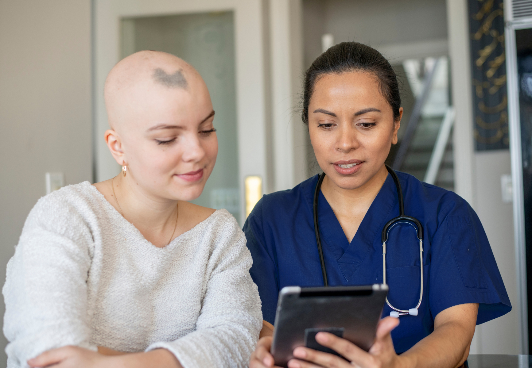 Oncology Nurse looking at mobile device with patient