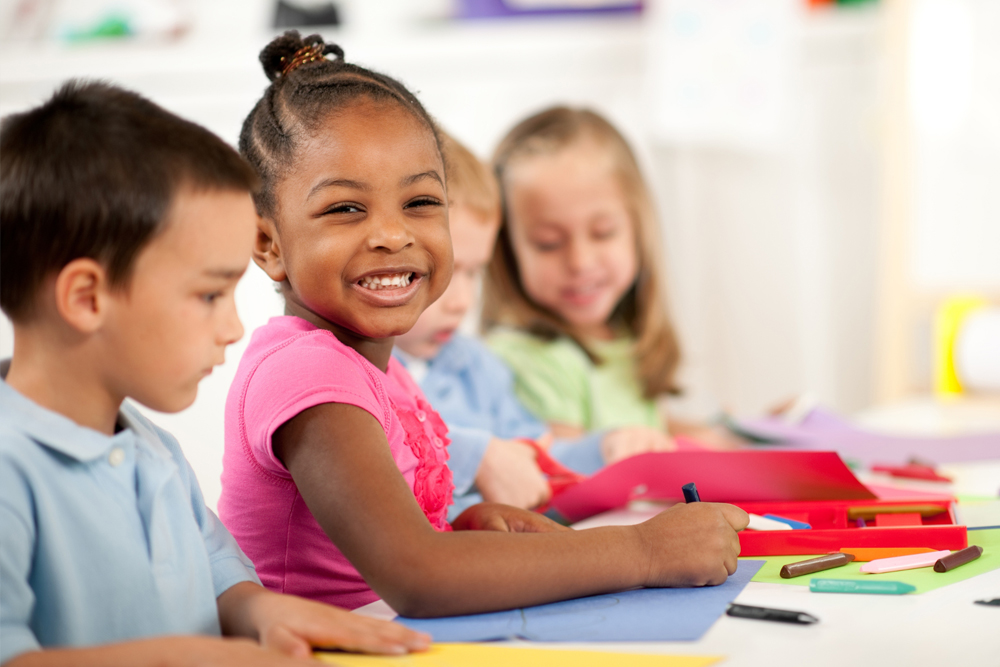 Small children playing at a table grinning