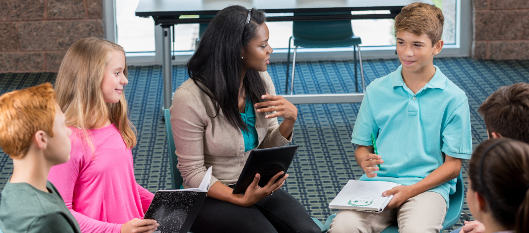 Nursing Student sitting with youths in a group discussion