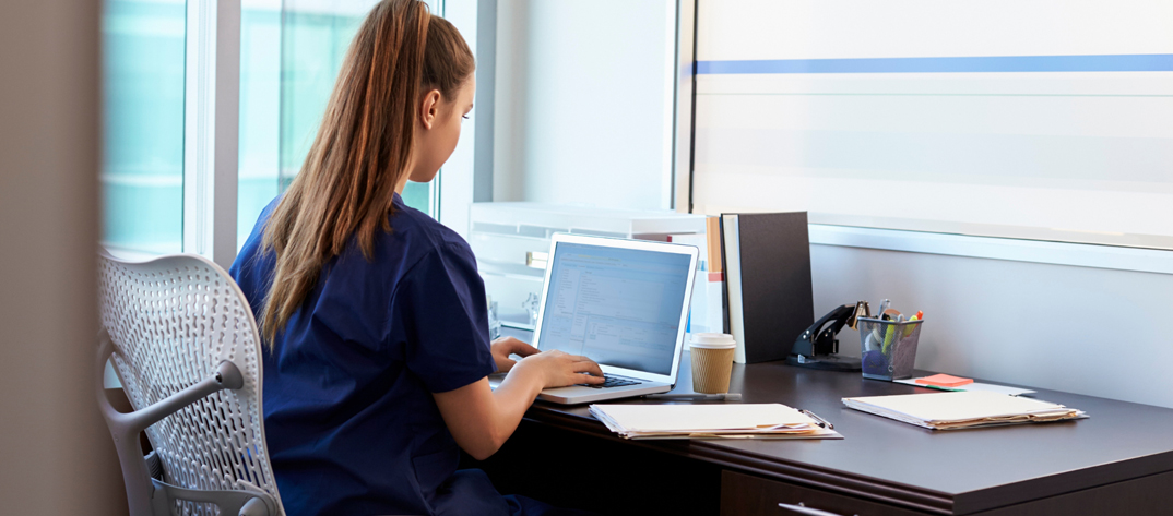 Nurse working at a laptop with back to the viewer