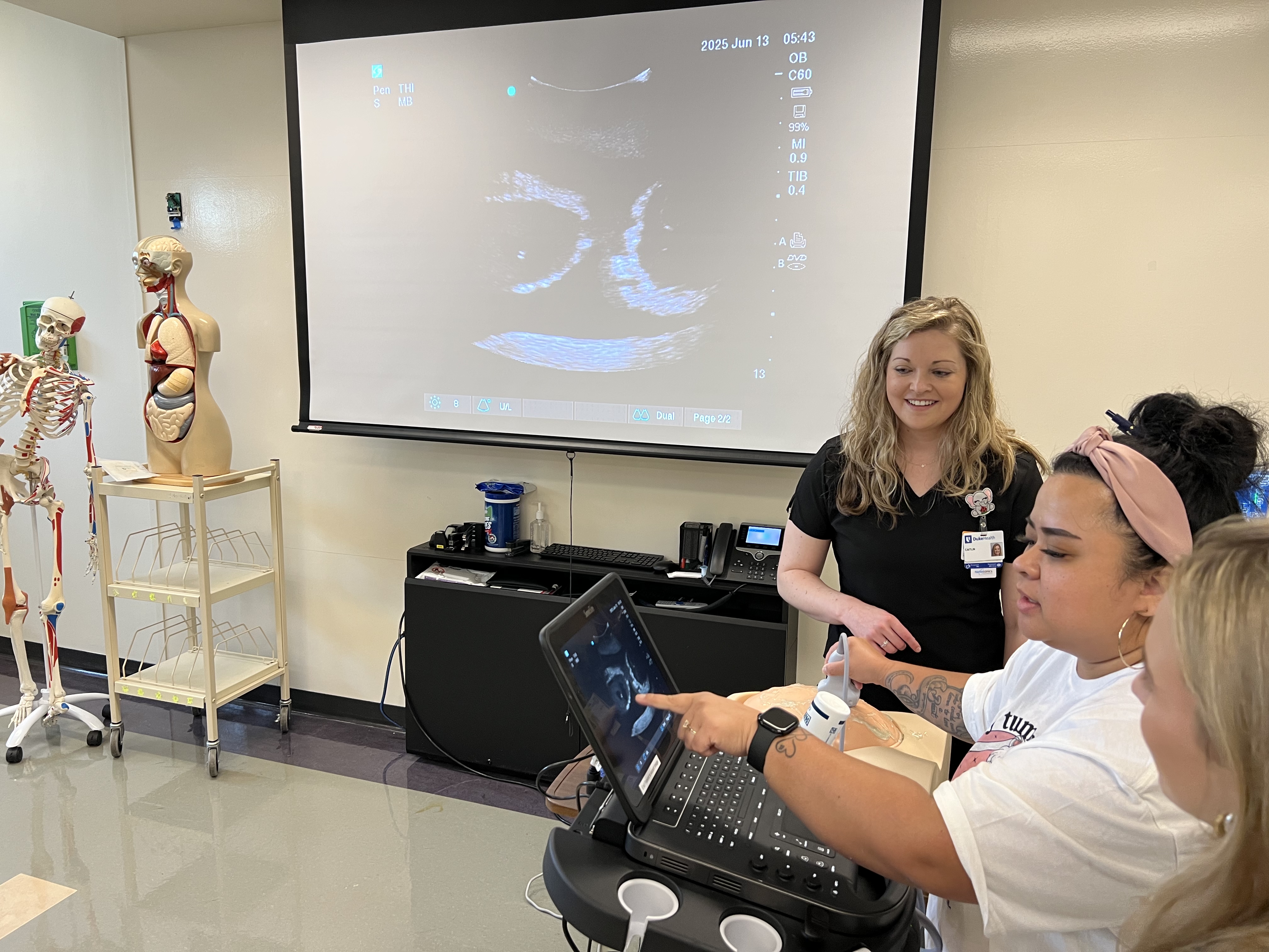 WHNP students practice using a transducer probe on a manikin of a pregnant belly