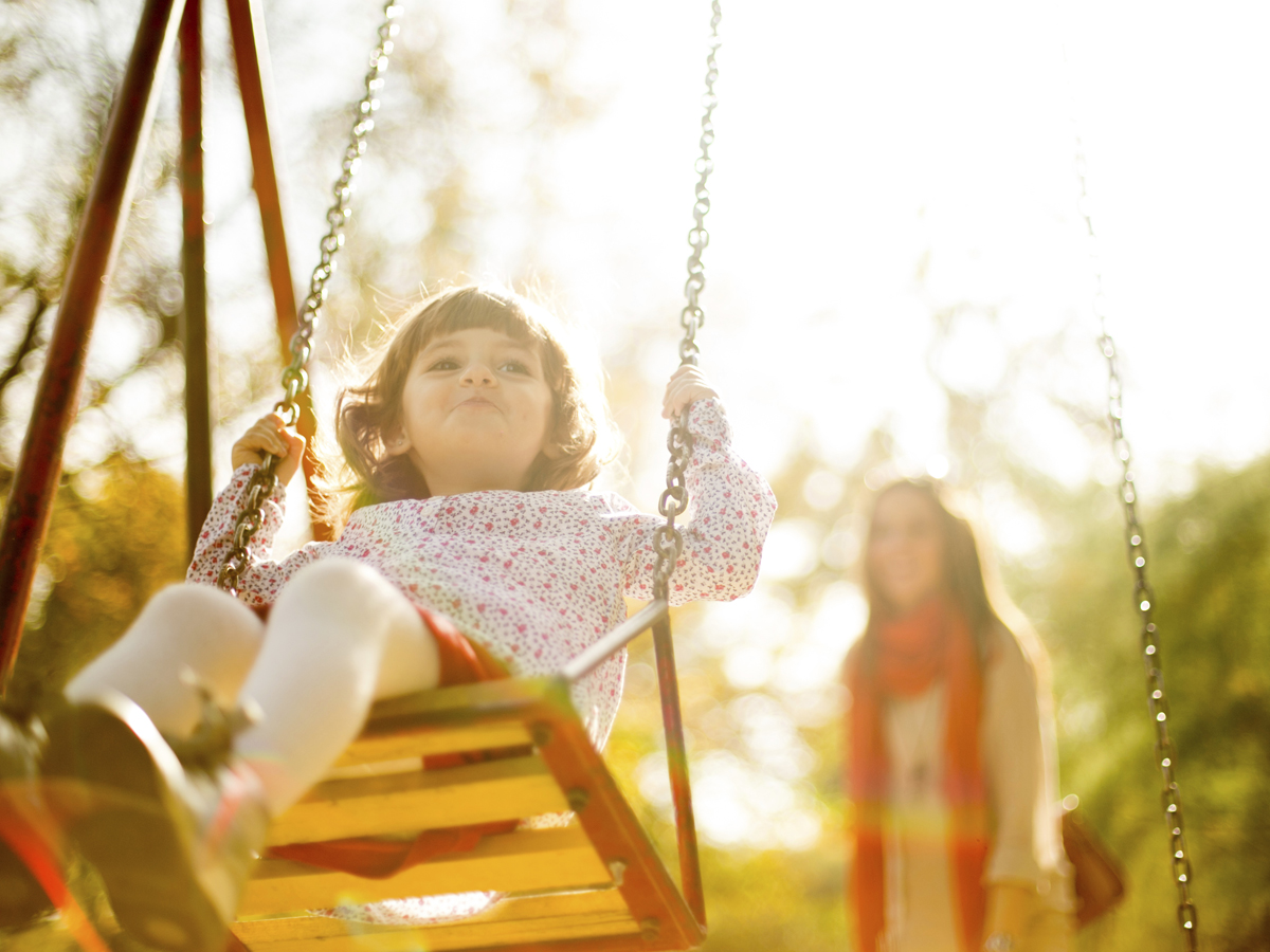 Child on swing with adult watching