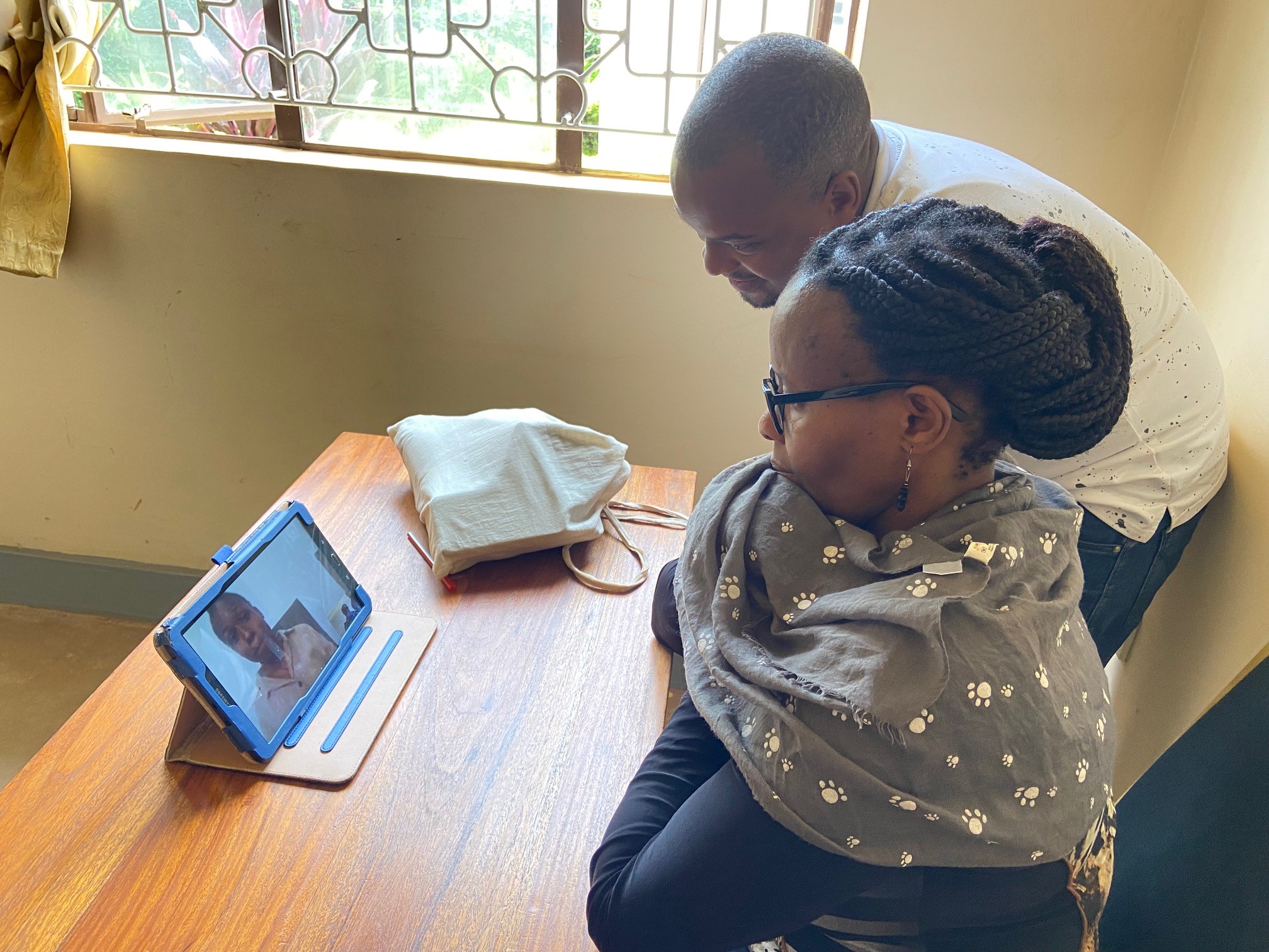 Two people interfact with a man on an iPad during a Telehealth visit