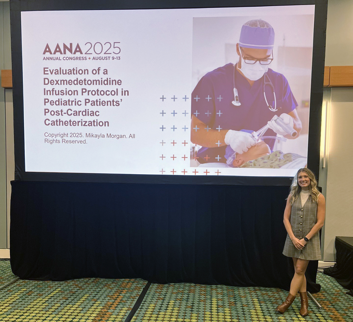 A student standing in front of a powerpoint presentation at a conference.