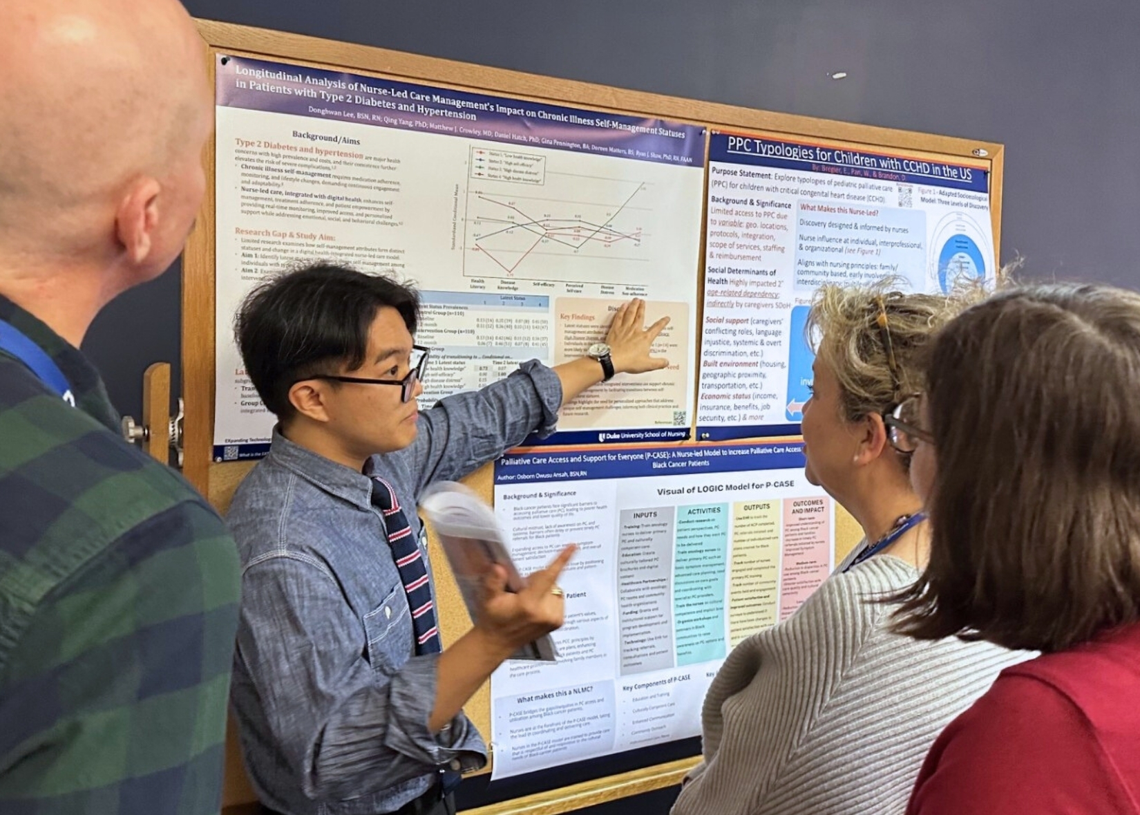 A student gestures towards a poster while others listen and watch.