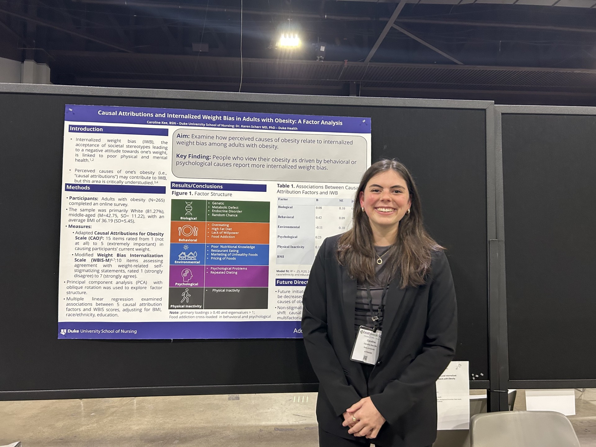 A student stands next to a research poster at a conference.