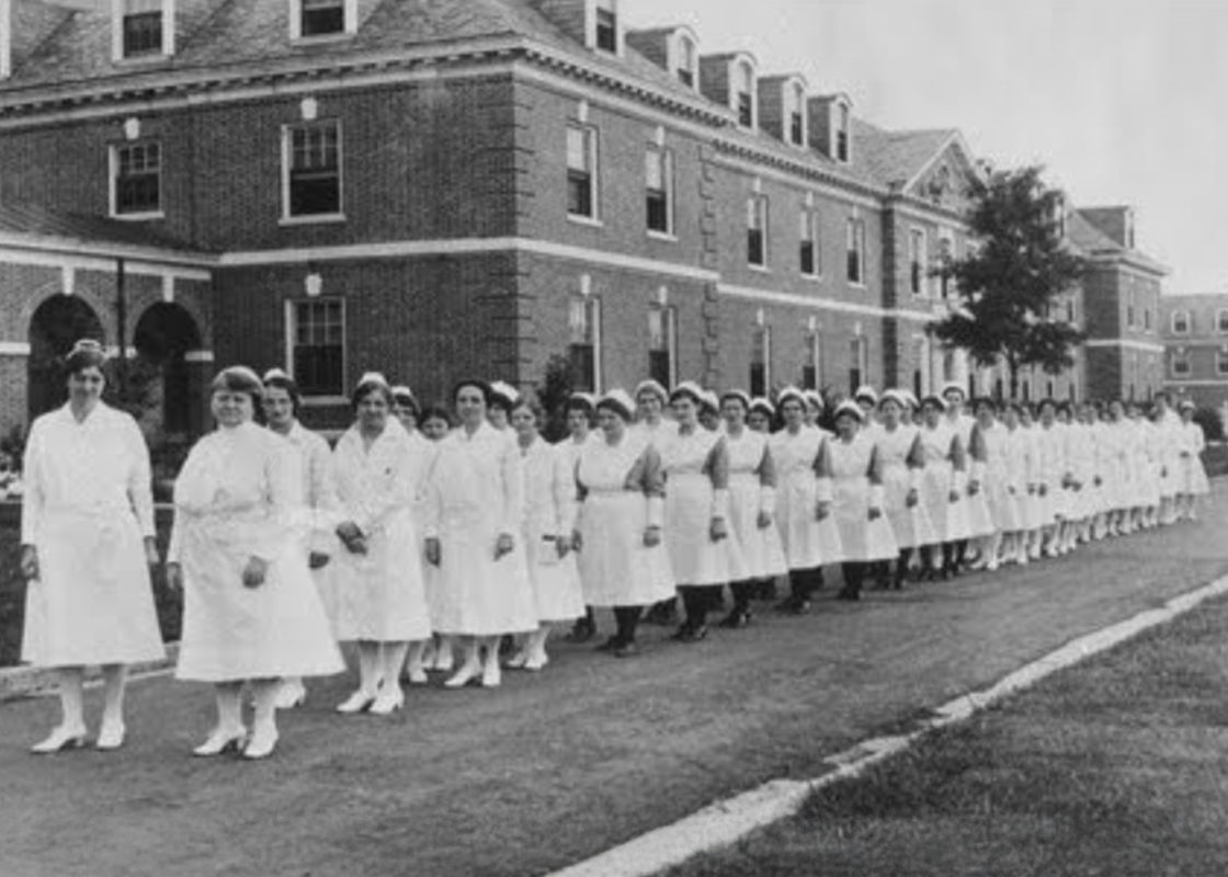 Women in the inaugural class of Duke University School of Nursing in 1931 stand in a line in white uniforms