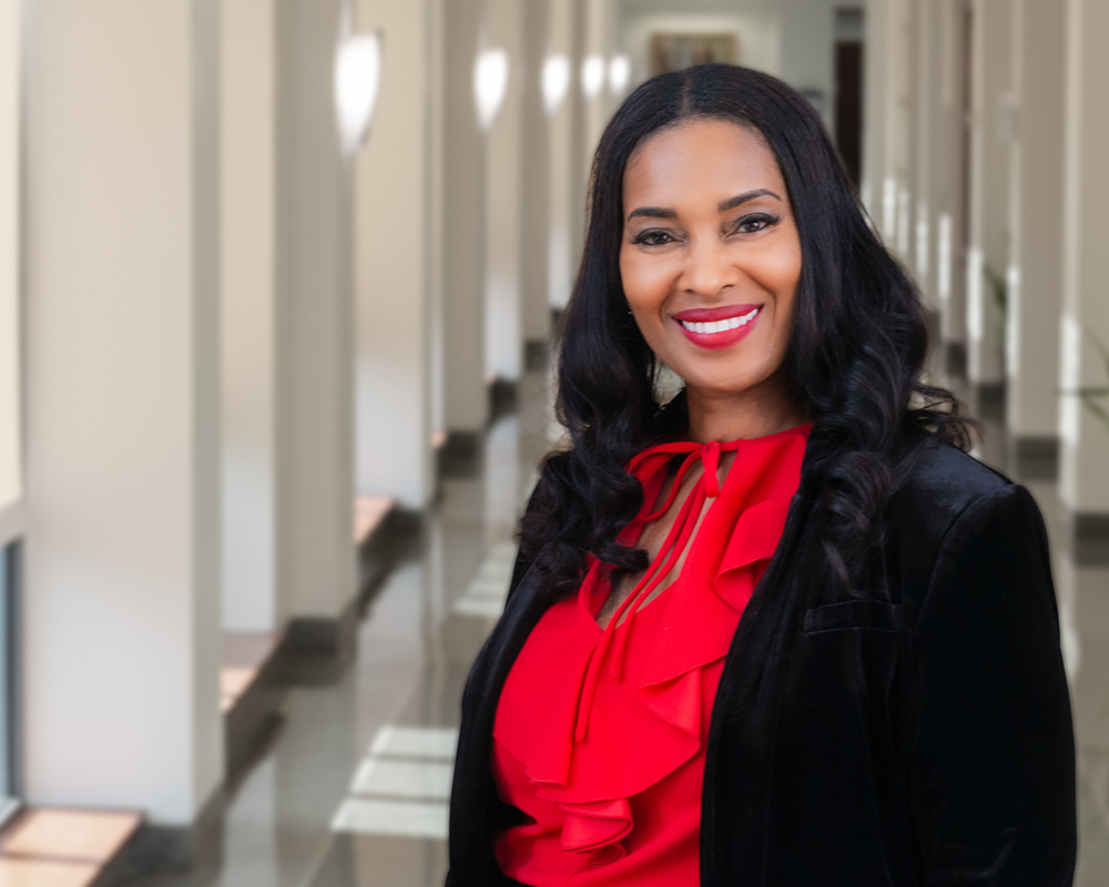 Dr. Schenita Randolph stands in a sunlit hallway smiling