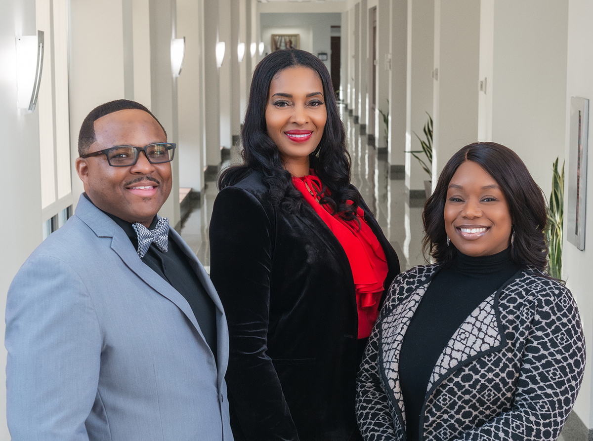 Drs. Michael Cary, Schenita Randolph, and Tolu Oyesanya stand in a sunlit hallway