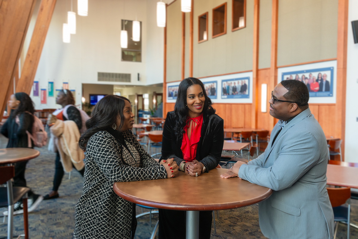 Dr. Tolu Oyesanya, Dr. Schenita Randolph, and Dr. Michael Cary talk around a table in the Atrium at the Duke University School of Nursing
