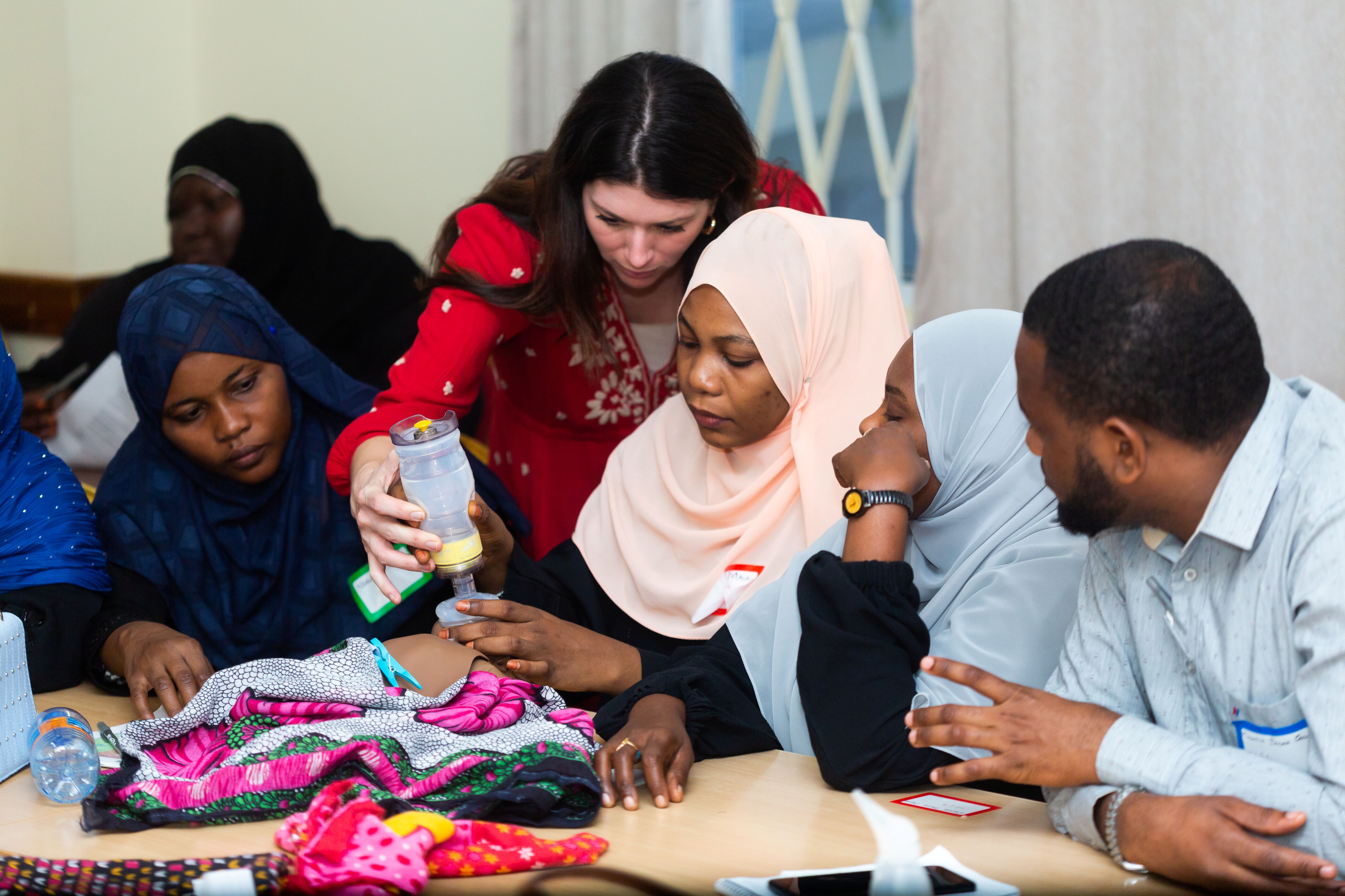 Gina Wilson bent over a table helping a midwife with infant resuscitation 