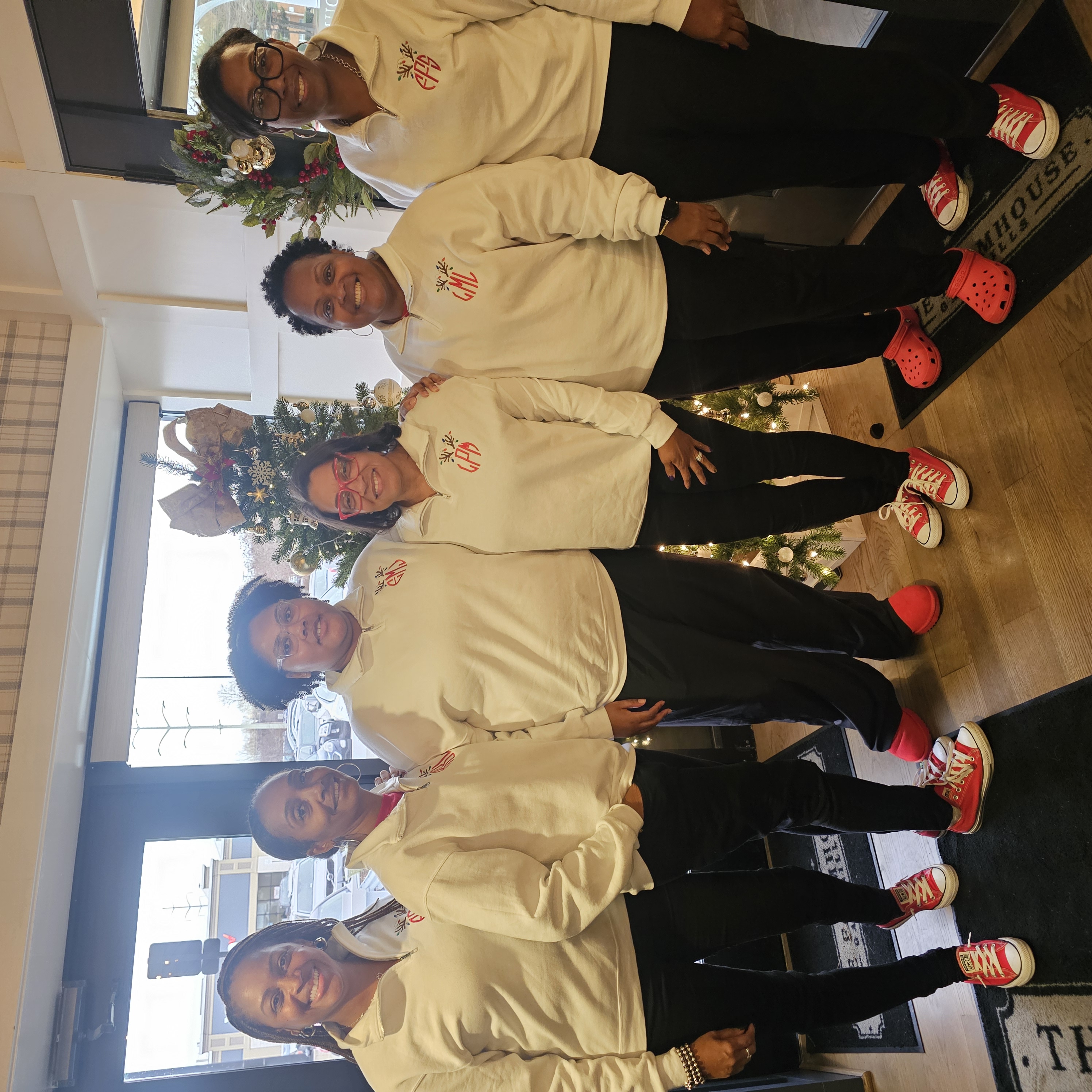 A group of people pose for a photo. They are wearing matching long sleeve white shirts.