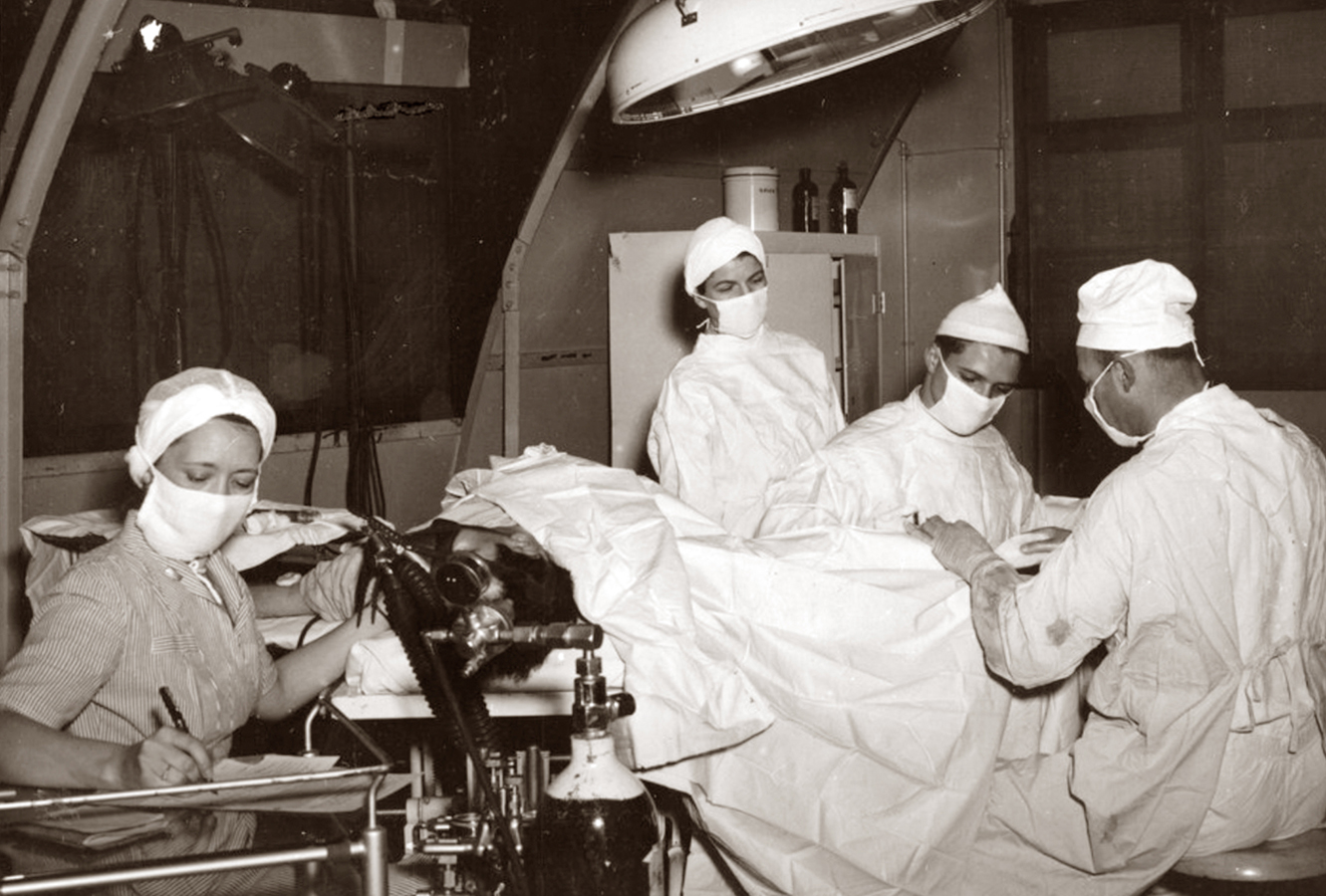 A black and white photo of nurses and surgeons in an operating room.