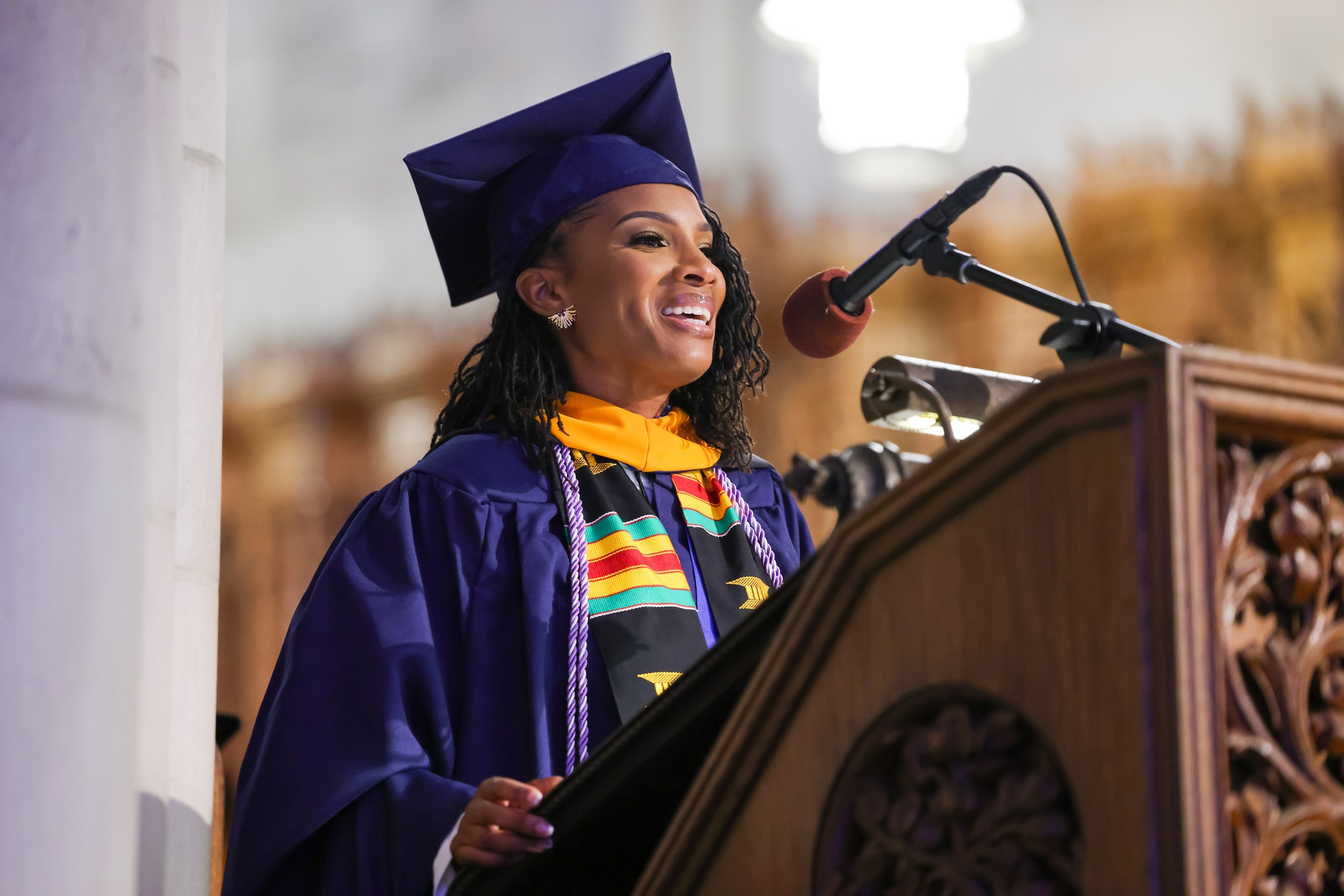 Lydia Nichols in graduation garb giving a commencement speech