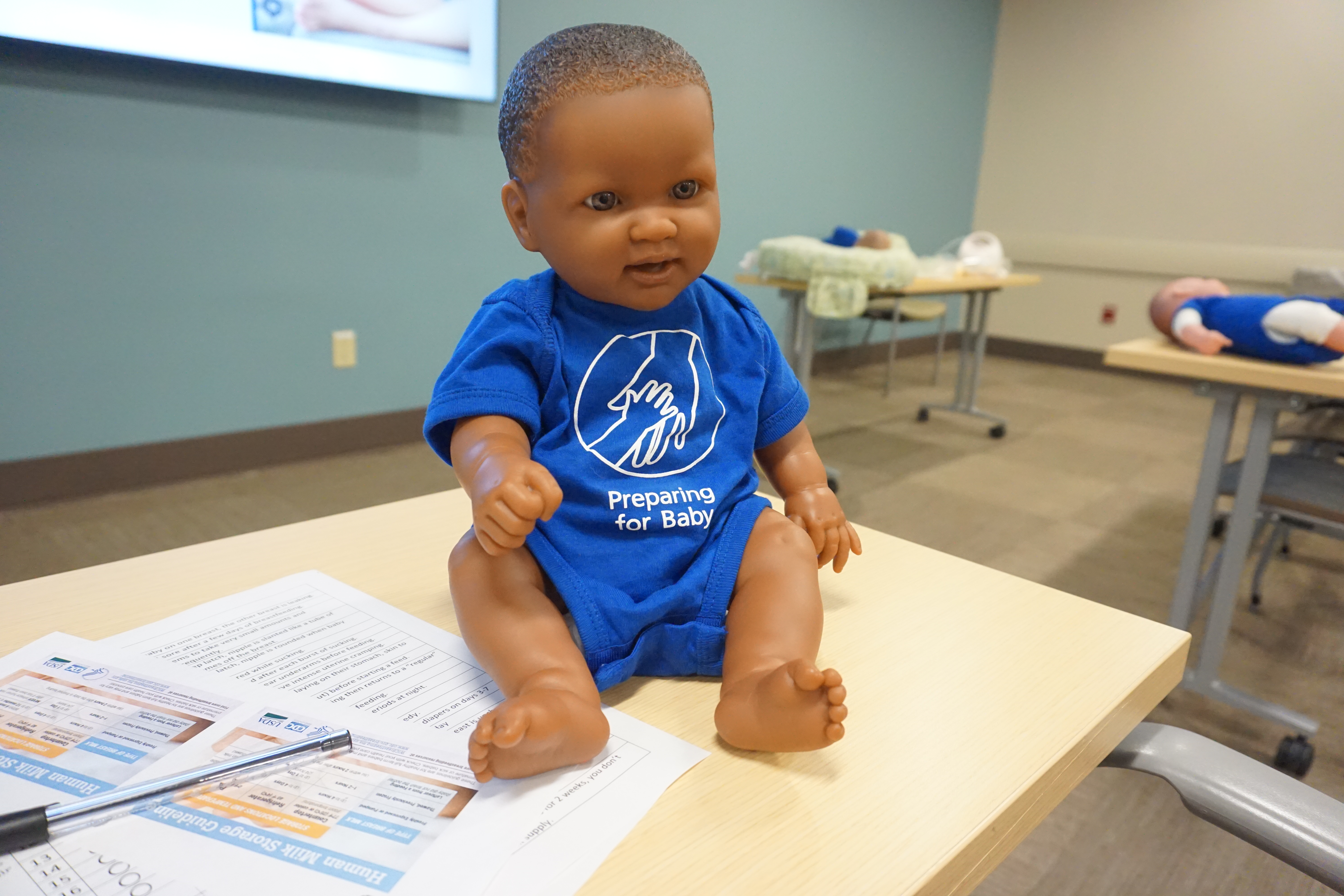 Baby doll wearing a blue "Preparing for Baby" shirt