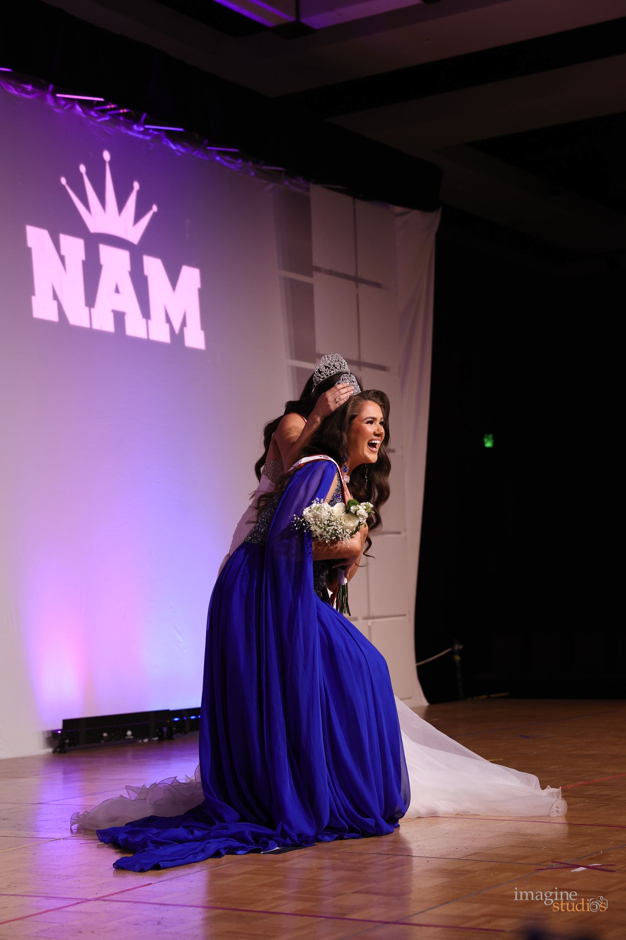 Reesa Artz on stage in a pageant bending down wearing a tiara