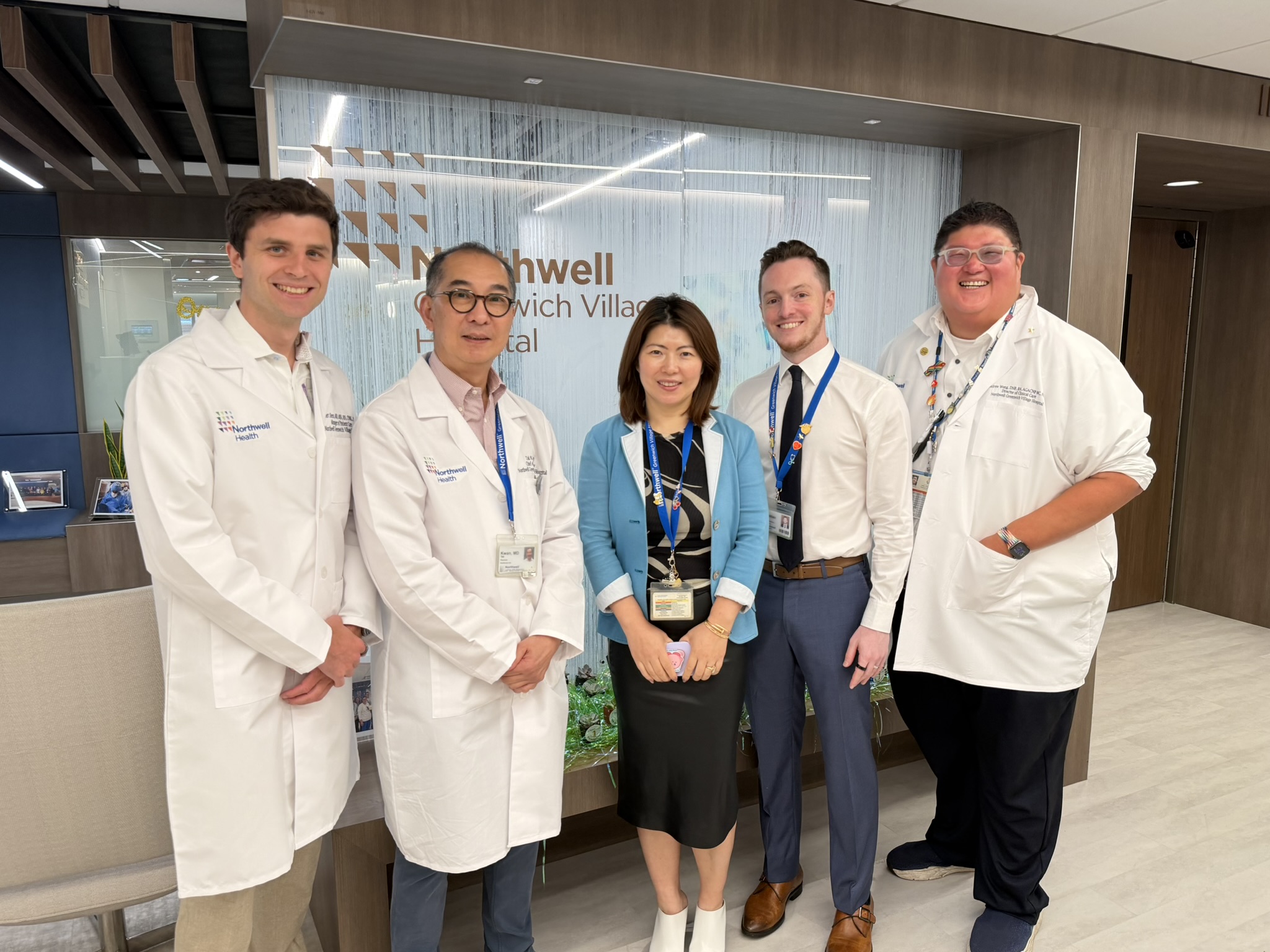 Five people, three of them in lab coats, posing for a photo inside a hospital