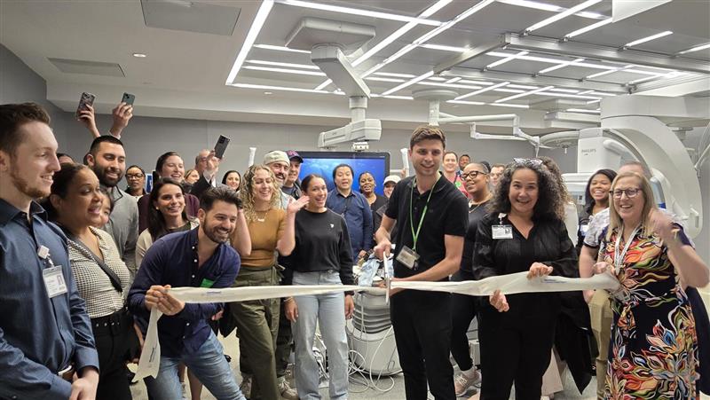 Group of people in a lab assembled around a ribbon cutting