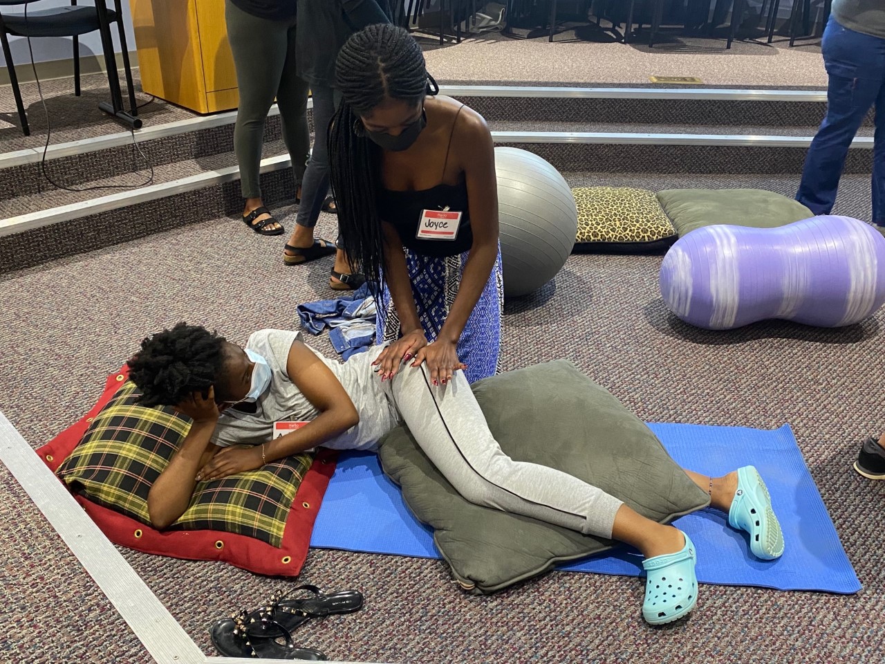 woman helps other woman relieve discomfort in hips during doula training