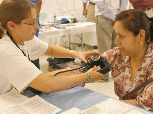 Student taking blood pressure at community event
