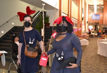 two students dressed in navy blue dresses and red bows with brooms