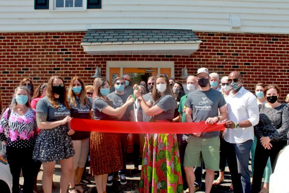 group of men and women standing outside at ribbon cutting