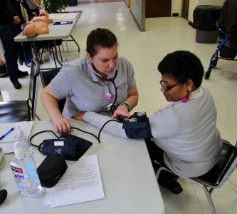 Student taking blood pressure of community member