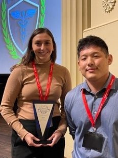 two students holding award at aamn conference