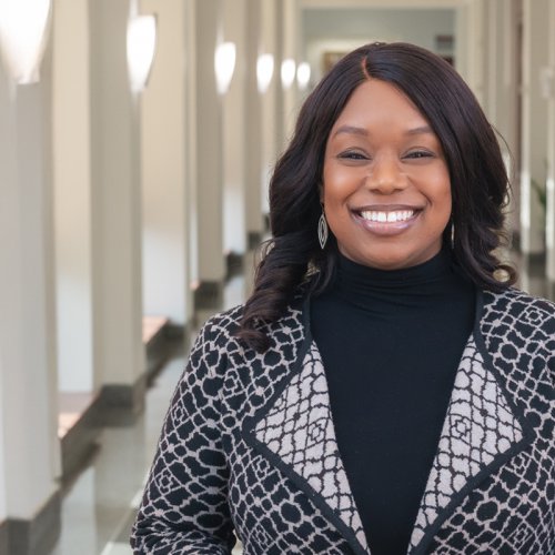 Dr. Tolu Oyesanya standing in a long, sunlit hallway