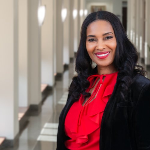 Dr. Schenita Randolph stands in a sunlit hallway smiling