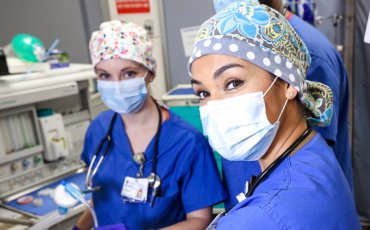 Two Duke CRNA Nurse Anesthesia Students in a simulated operating room environment wearing blue scrubs and masks.