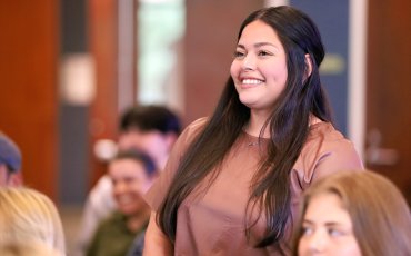 School of Nursing Student stands in a classroom smiling