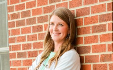 Shannon Allison leaning against a brick wall