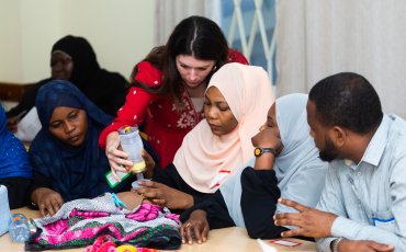 Gina Wilson bent over a table helping a midwife with infant resuscitation 