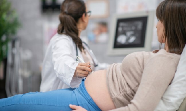 A nurse or doctor gives a pregnant woman an ultrasound.