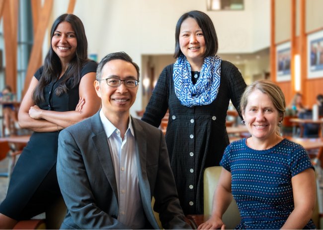 Four nursing faculty pose together in the school's atrium