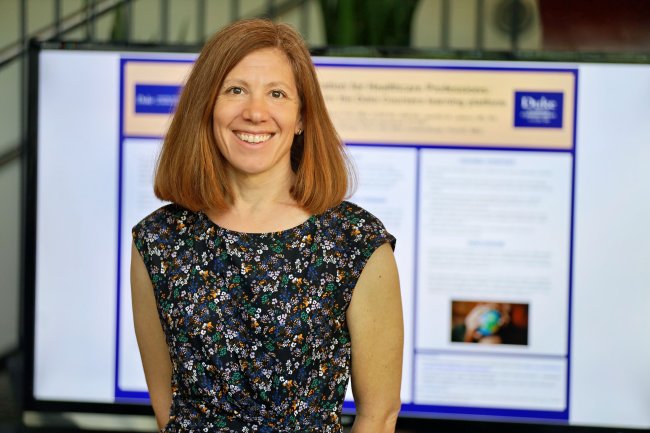 AnnMarie Walton smiling in front of poster