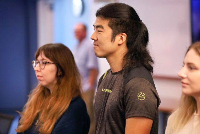 Three students stand in profile, looking at something in the Center for Nursing Discovery